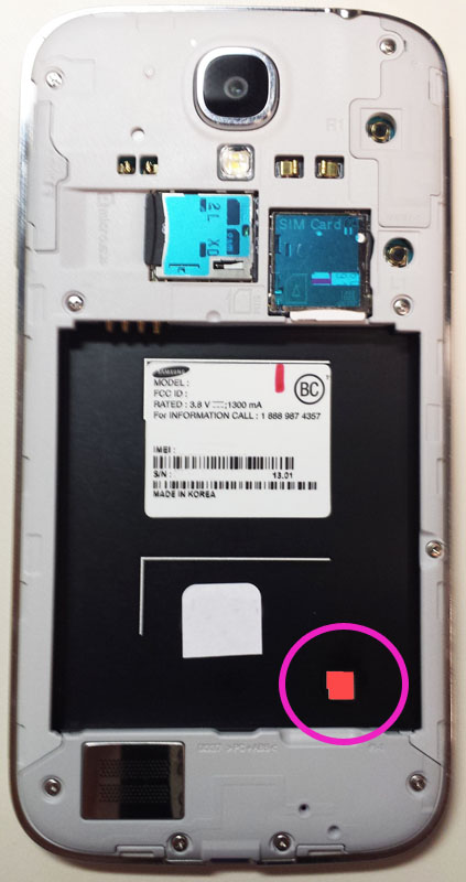 Prikaz zadnje strane Samsung telefona na kojem je senzor vlage aktiviran što se vidi po crvenoj boji indikatora koji je bele boje ako nije došao u kontakt sa vodom